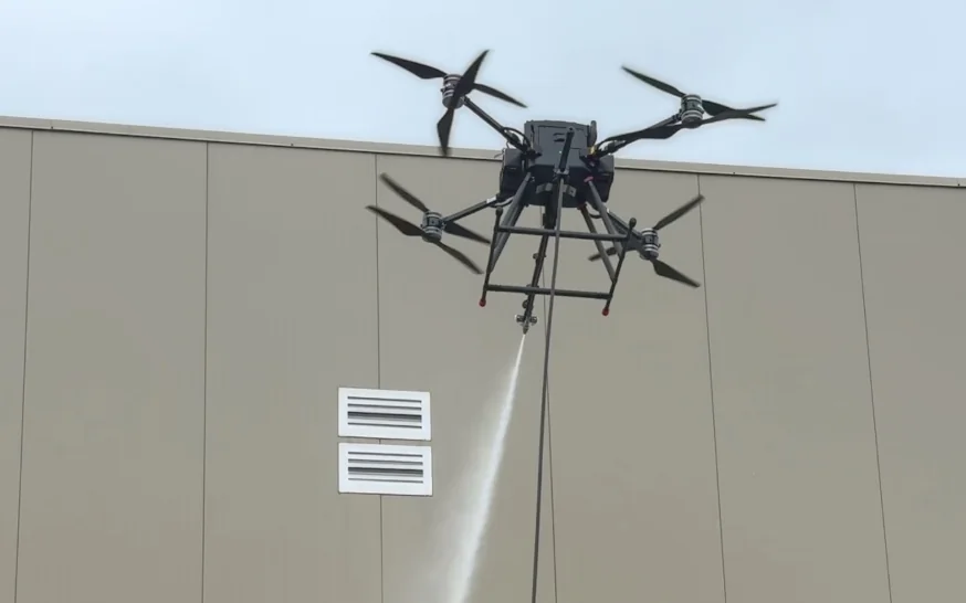 Drone de nettoyage H2O Drone projetant un jet d’eau contre une façade de bâtiment commercial