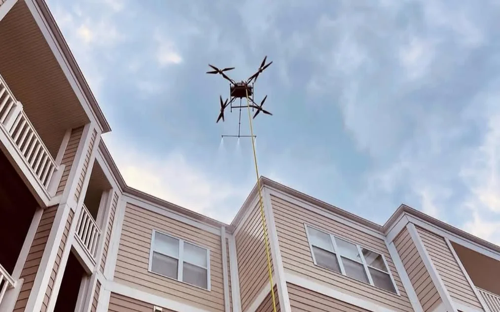 Drone de nettoyage H2O Drone au-dessus d’un immeuble résidentiel avec son tuyau et son jet d’eau